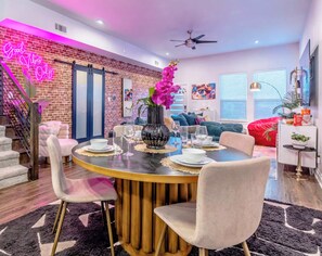 A modern dining area with a round table, chairs, and a vase of flowers. - Family & Friends Retreat, Hot Tub + Arcade + Cinema (Dallas)
