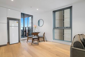 Een moderne keuken met een inbouwkoelkast, een eethoek met een ronde tafel en stoelen, en grote ramen met uitzicht op de stad.