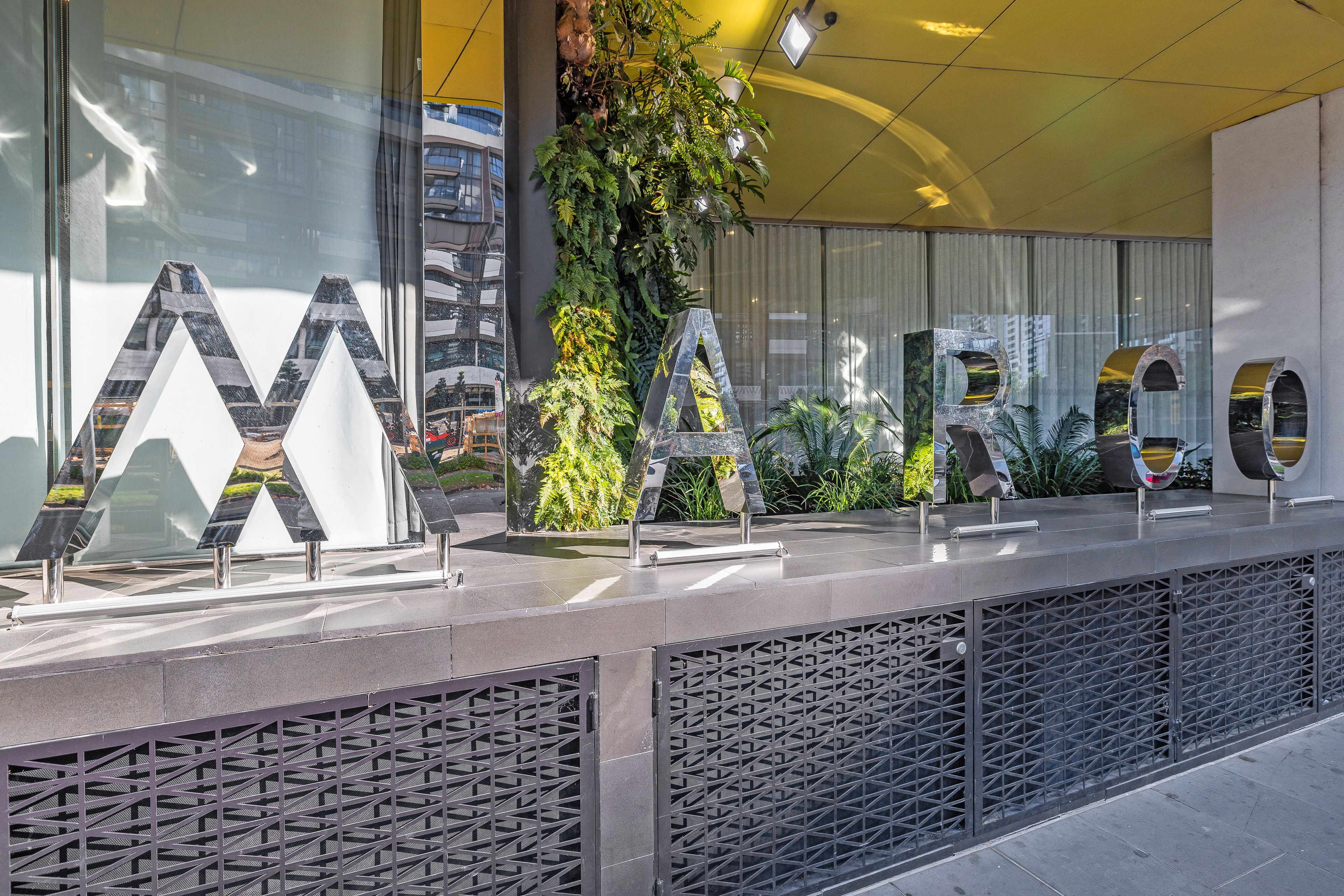 A reception desk with large letters spelling 'MARCO' and a vertical garden behind it.