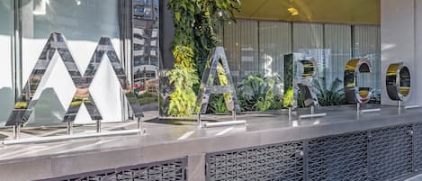 A reception desk with large letters spelling 'MARCO' and a vertical garden behind it.