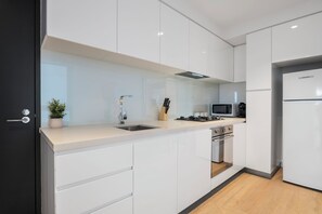 Eine moderne Küche mit weißen Schränken, einer Edelstahl-Spüle, einer Mikrowelle und einem eingebauten Backofen.