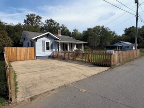 A residential property with a single-story house, a fenced driveway, and a mailbox. - Charming Blue Cottage - Walking Distance to Downtown (Waynesville)