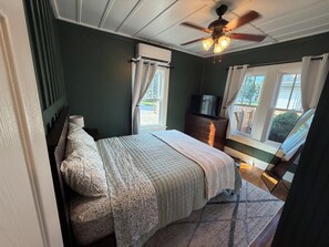 Quarto com cama, penteadeira, televisão e ventoinha de teto.