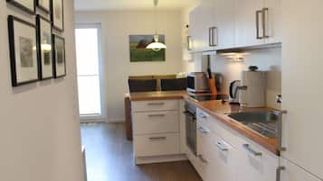 Een moderne keuken met witte kastjes, een houten aanrechtblad en een ingebouwde oven.