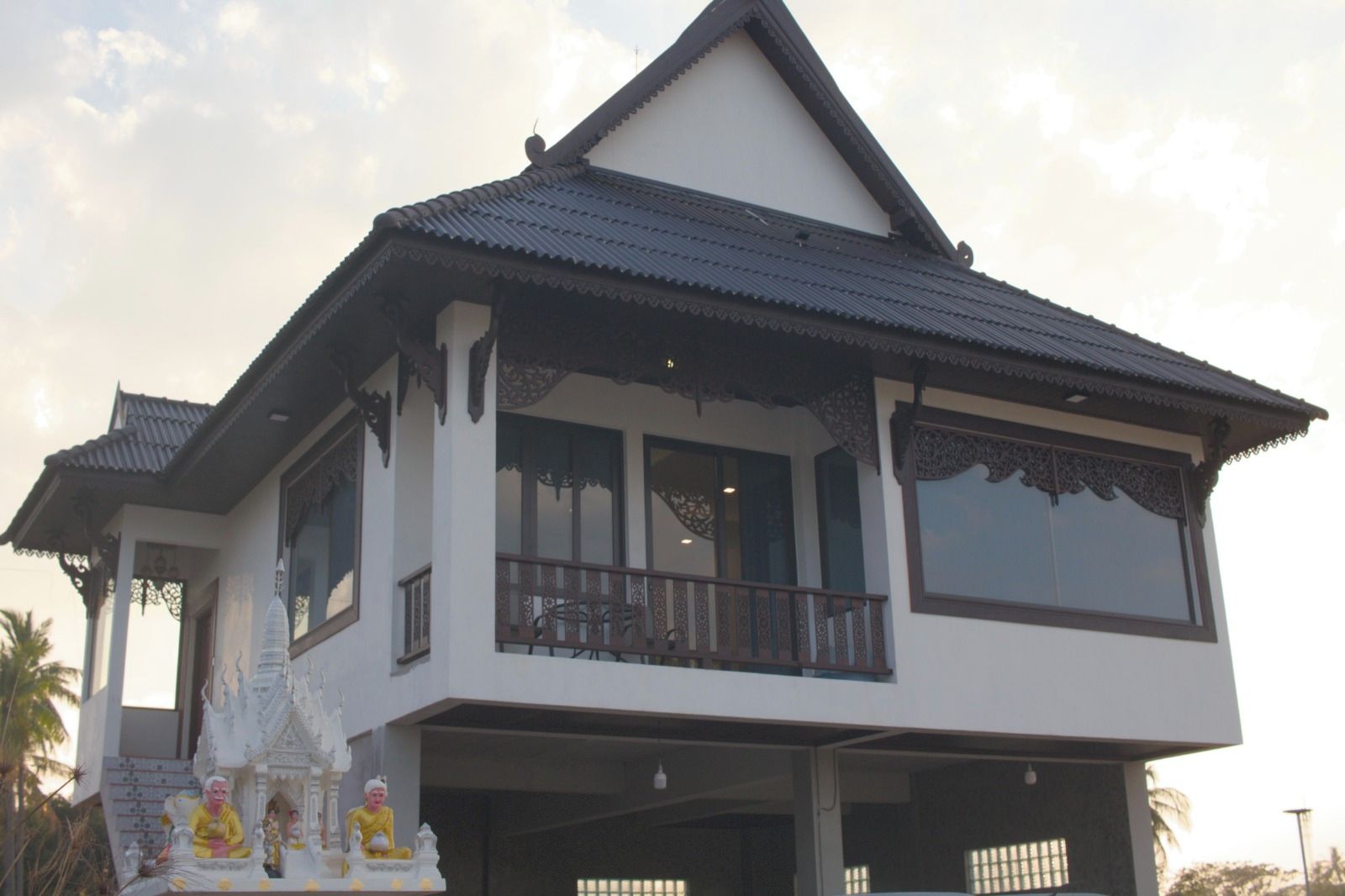 Une maison à deux étages dotée d’un balcon et d’un petit autel décoratif à l’entrée.