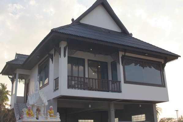 Una casa de dos pisos con un balcón y un santuario decorativo en la entrada.