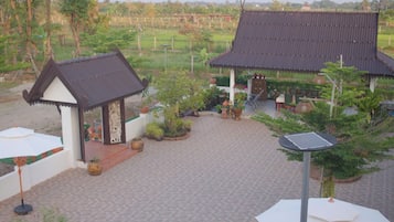 A courtyard with traditional-style pavilions, a paved walkway, and a variety of potted plants.