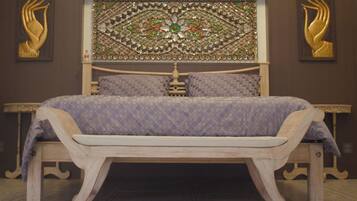 Un lit avec une couvre-lit à motifs, une tête de lit décorative et un banc en bois placé devant.