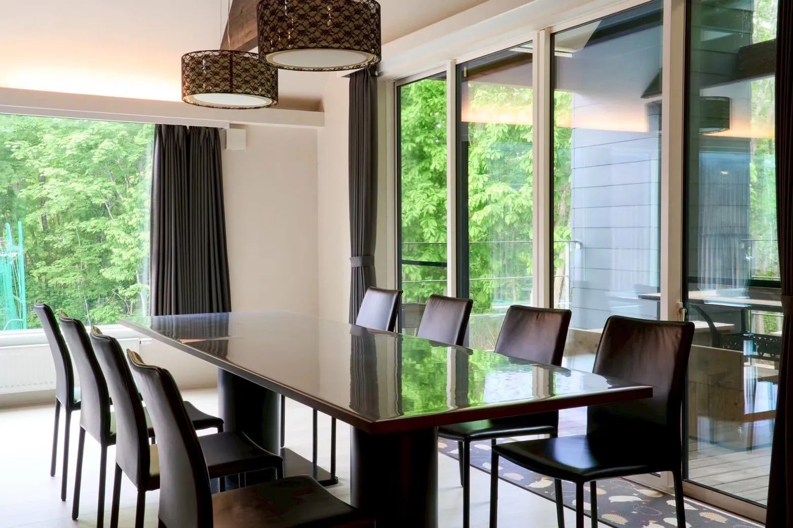 A conference room with a glass table and chairs, large windows, and hanging lamps.