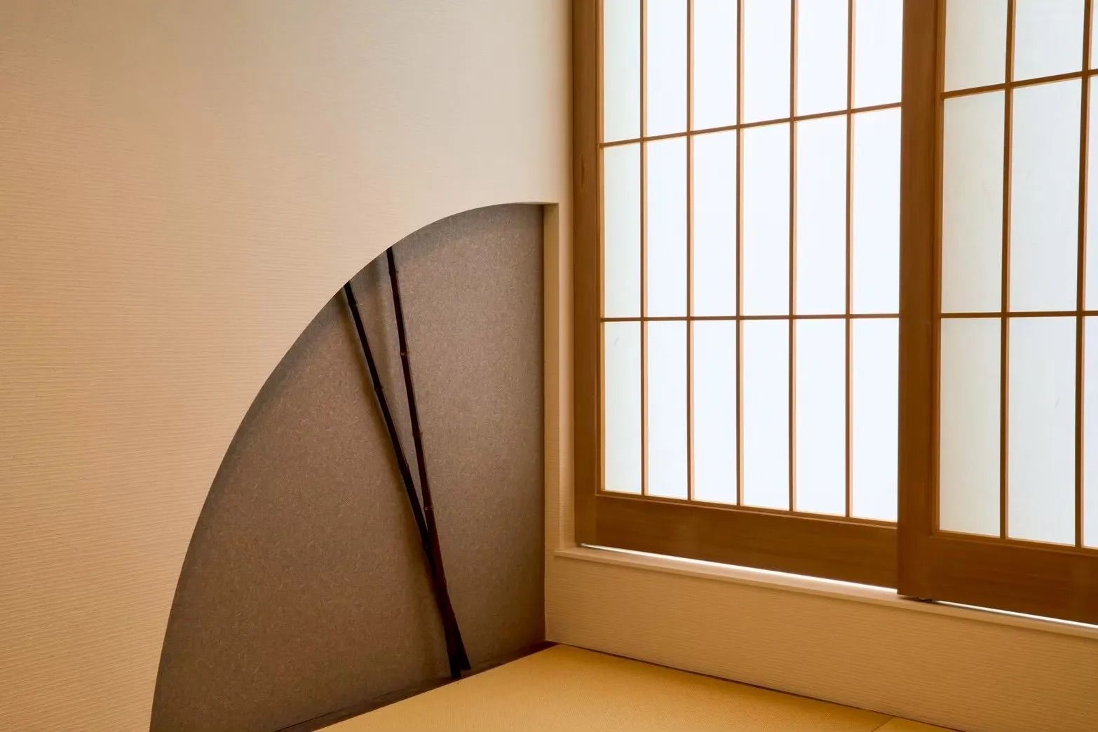 A corner of a room with a window featuring a grid pattern and a curved wall.