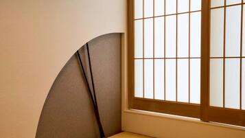 A corner of a room with a window featuring a grid pattern and a curved wall.