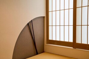 Un coin de pièce avec une fenêtre à motifs géométriques et un mur incurvé.