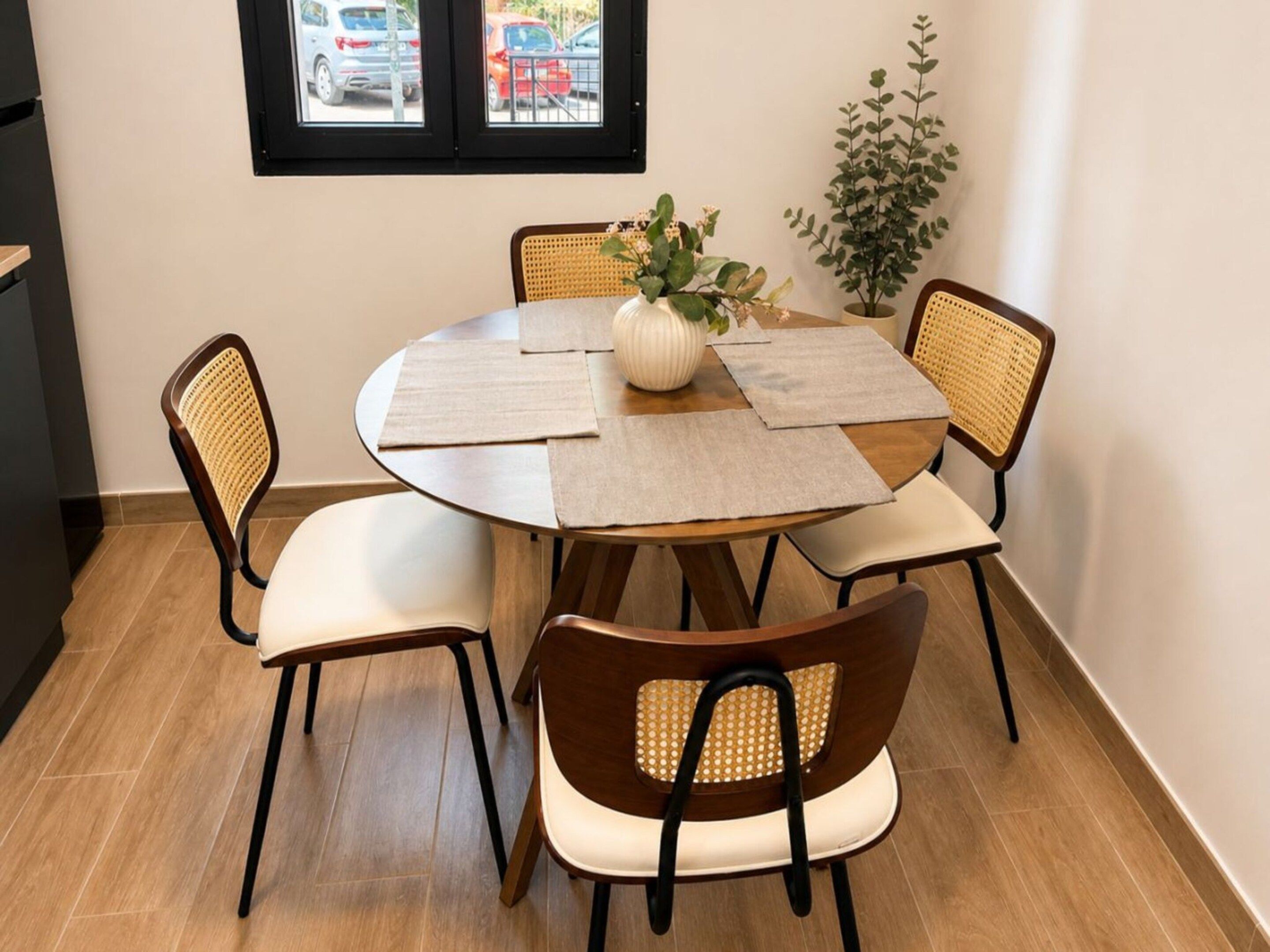 Un comedor con una mesa redonda, cuatro sillas y una planta en maceta.