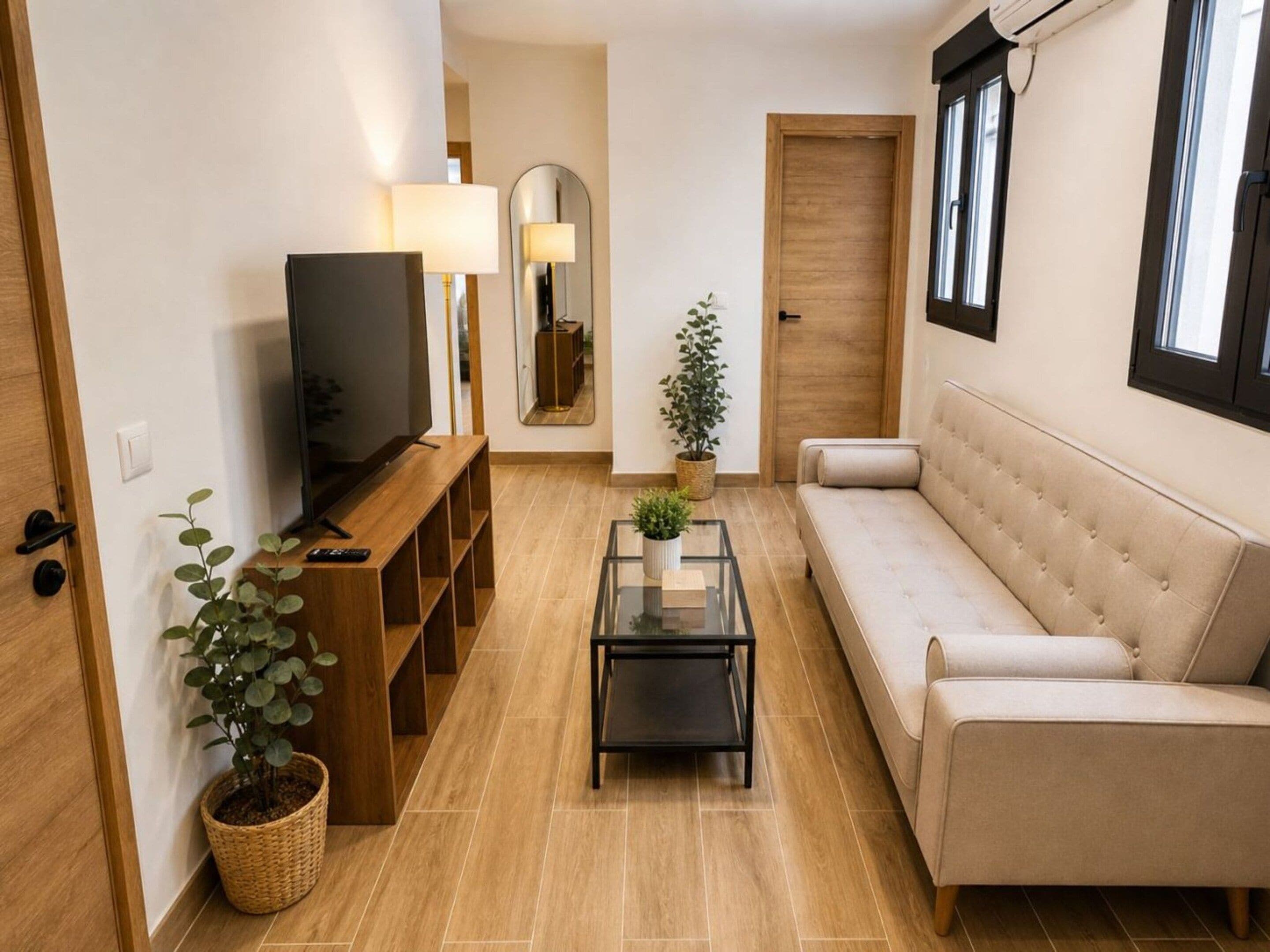A modern living room with a sofa, a coffee table, a TV, and a mirror.