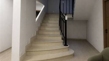 A staircase with a black railing, beige carpeted steps, and a light-colored floor.