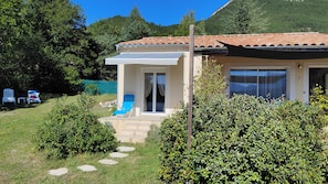 A house with a patio, a covered entryway, and a view of the surrounding greenery and mountains. - Charming single-family home, 70 m2, on enclosed property, in a completely quiet setting (Saint-André-les-Alpes)