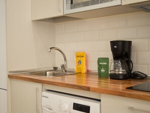 A kitchen with a stainless steel sink, a coffee maker, and two welcome bags on the countertop. - Stay in Quiet Madrid Area (Madrid)