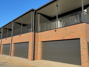 A building with a brick facade, two garage doors, and a balcony with metal railings. - Summons Fourteen - Sleeps 8 (Wagga Wagga)