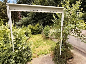 A garden with a pergola structure surrounded by various shrubs and trees. - Apartment With Mezzanine, Mont-dore (Mont-Dore)