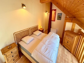 A bedroom with a wooden bed, bedside tables, and a wooden dresser. - Apartment With Mezzanine, Mont-dore (Mont-Dore)
