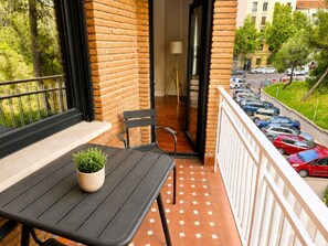 A balcony with a table, chairs, and a potted plant. - Spacious Madrid Apartment With Garden (Madrid)
