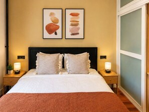 A hotel room with a bed, two nightstands, a wall-mounted lamp, and a window. - Spacious Madrid Apartment With Garden (Madrid)
