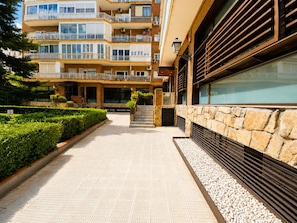 A multi-story residential building with a central staircase, a stone facade, and a landscaped garden area. - Spacious Madrid Apartment With Garden (Madrid)