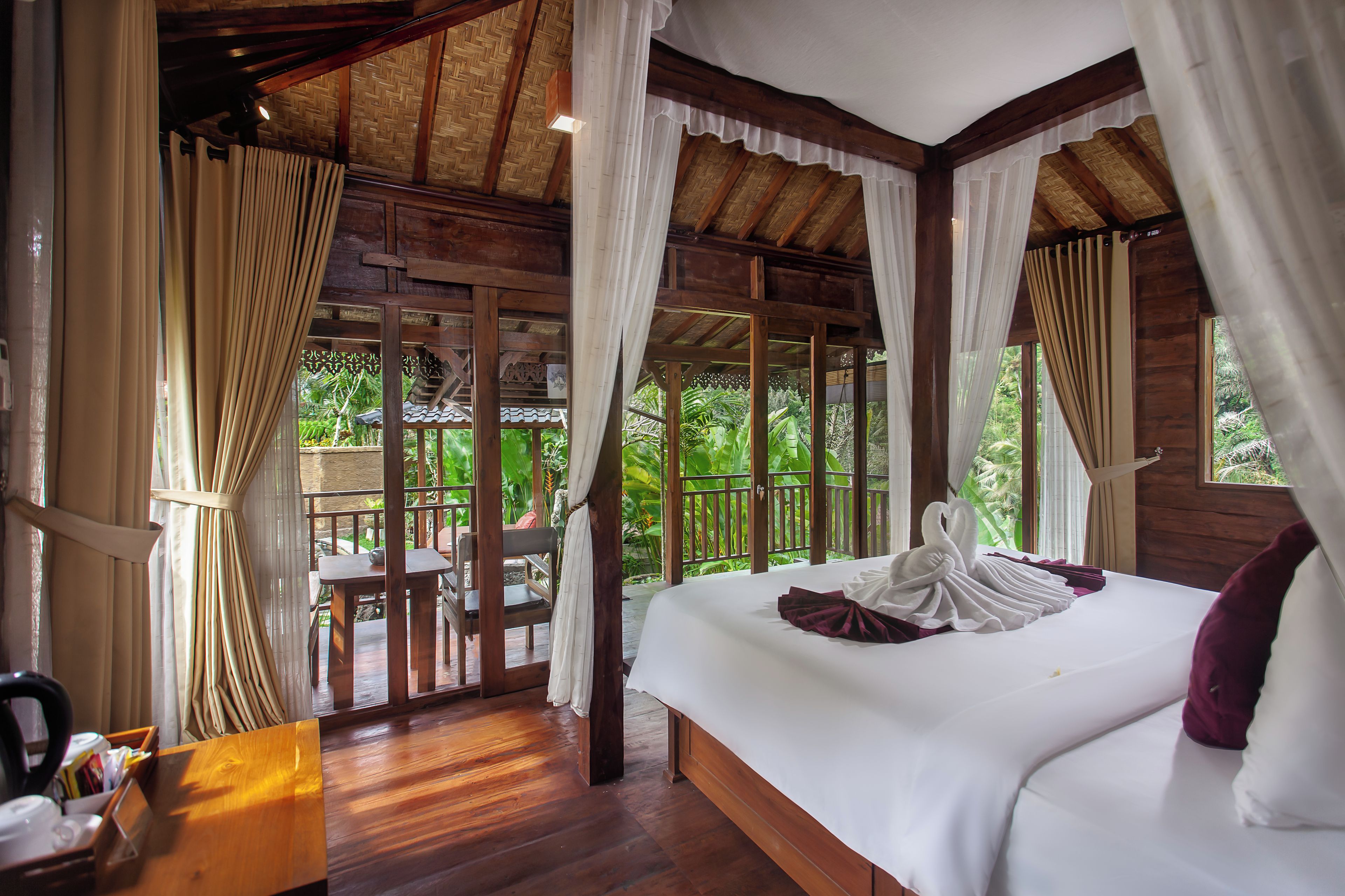 A room with a bed, wooden furniture, and a view of greenery outside.