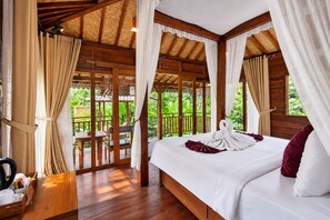 Quarto de madeira com cama, cortinas e vista para o verde.