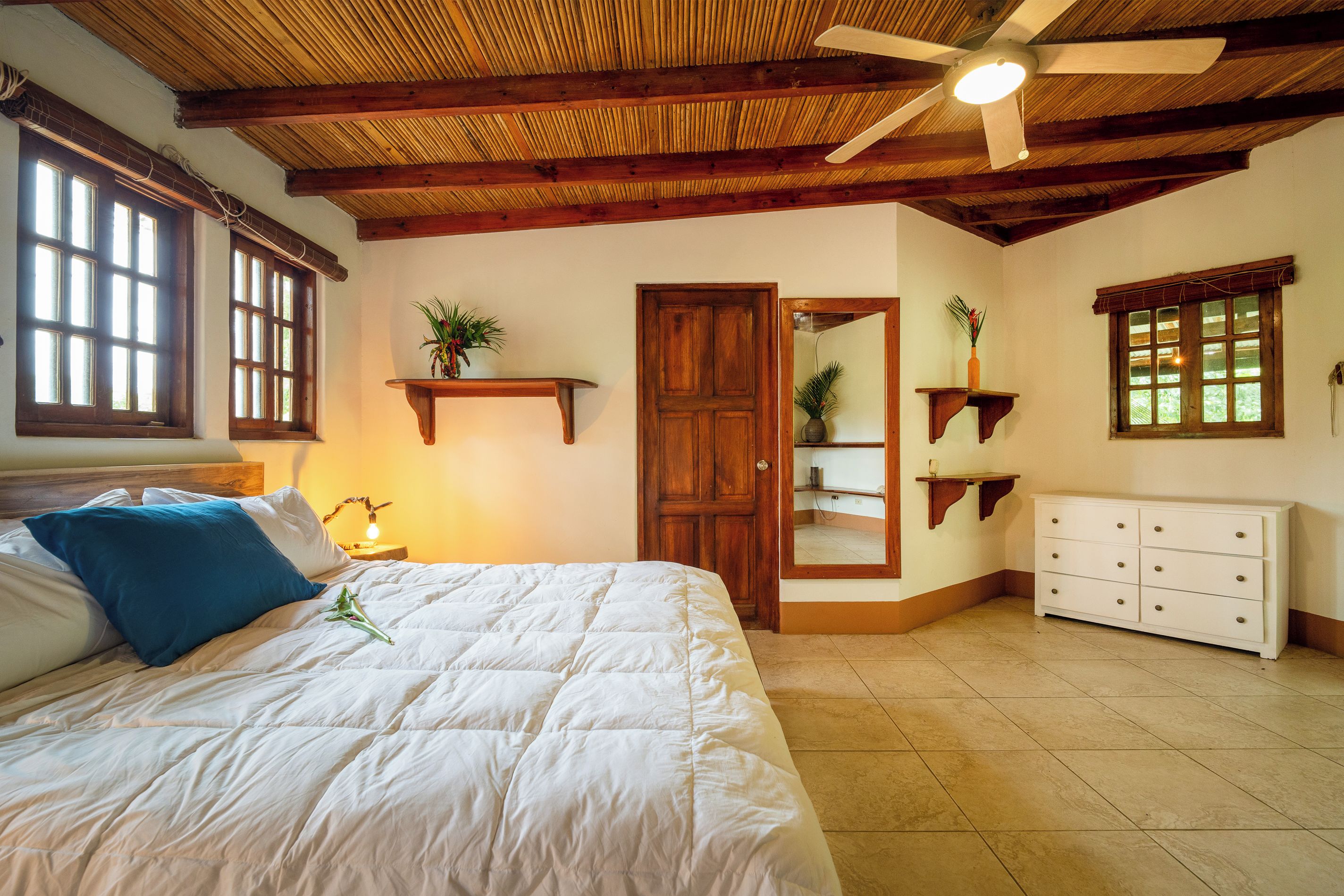 A bedroom with a bed, a nightstand, a ceiling fan, and a dresser.