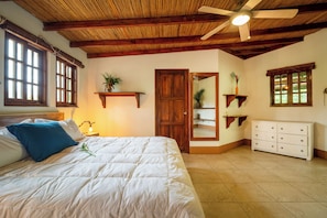 A bedroom with a bed, a nightstand, a ceiling fan, and a dresser.