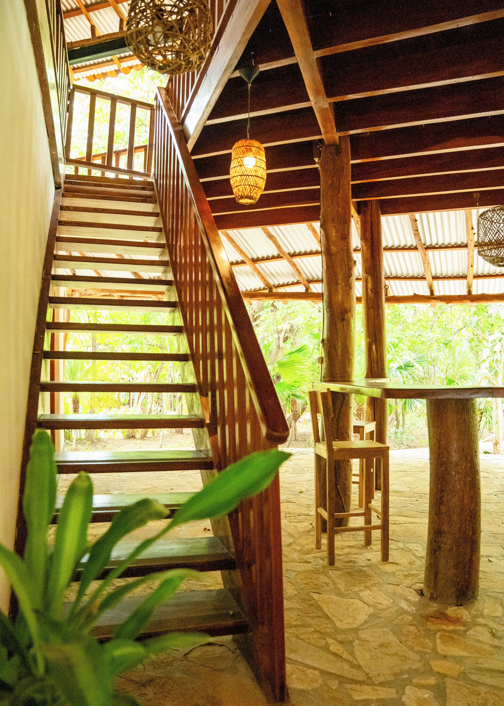 A wooden staircase leading to a covered outdoor area with a table and chairs.
