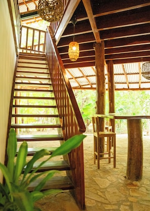 A wooden staircase leading to a covered outdoor area with a table and chairs.