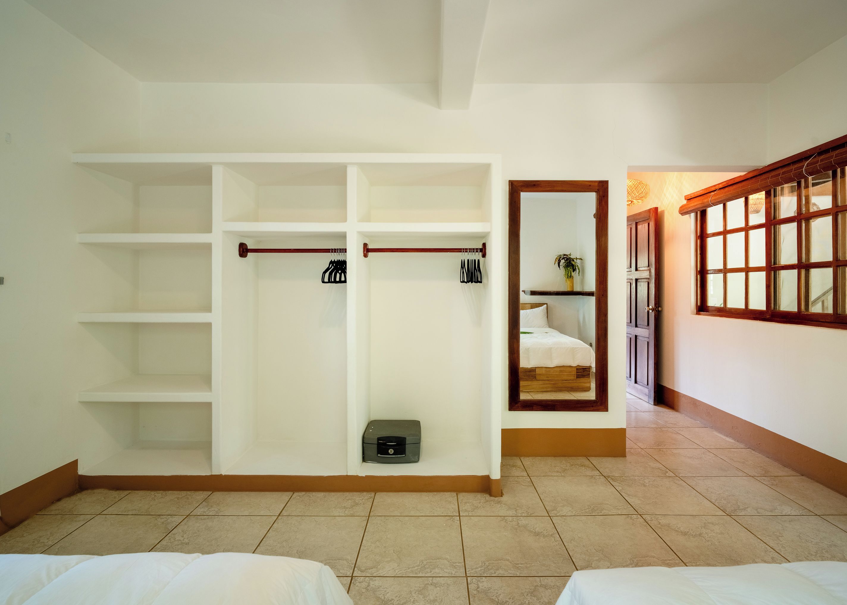 Habitación de hotel con un amplio vestidor, una cama, un pequeño rincón de descanso y un ventanal con vistas.