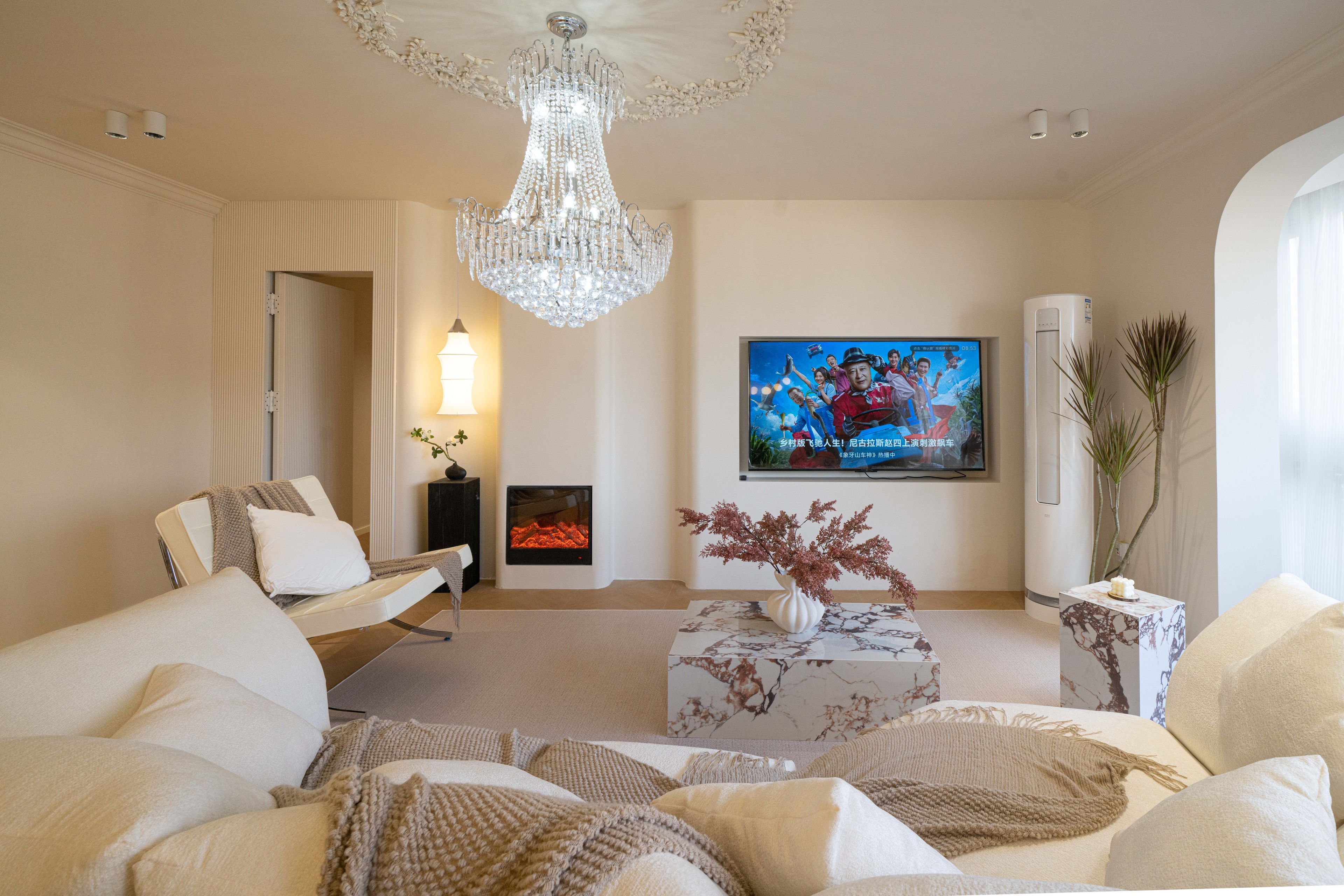 Un soggiorno moderno con un lampadario, una televisione a schermo piatto e un camino.