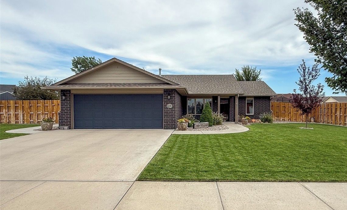 A single-story house with a garage, a well-maintained lawn, and a wooden fence.