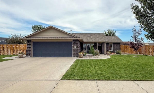 A single-story house with a garage, a well-maintained lawn, and a wooden fence.