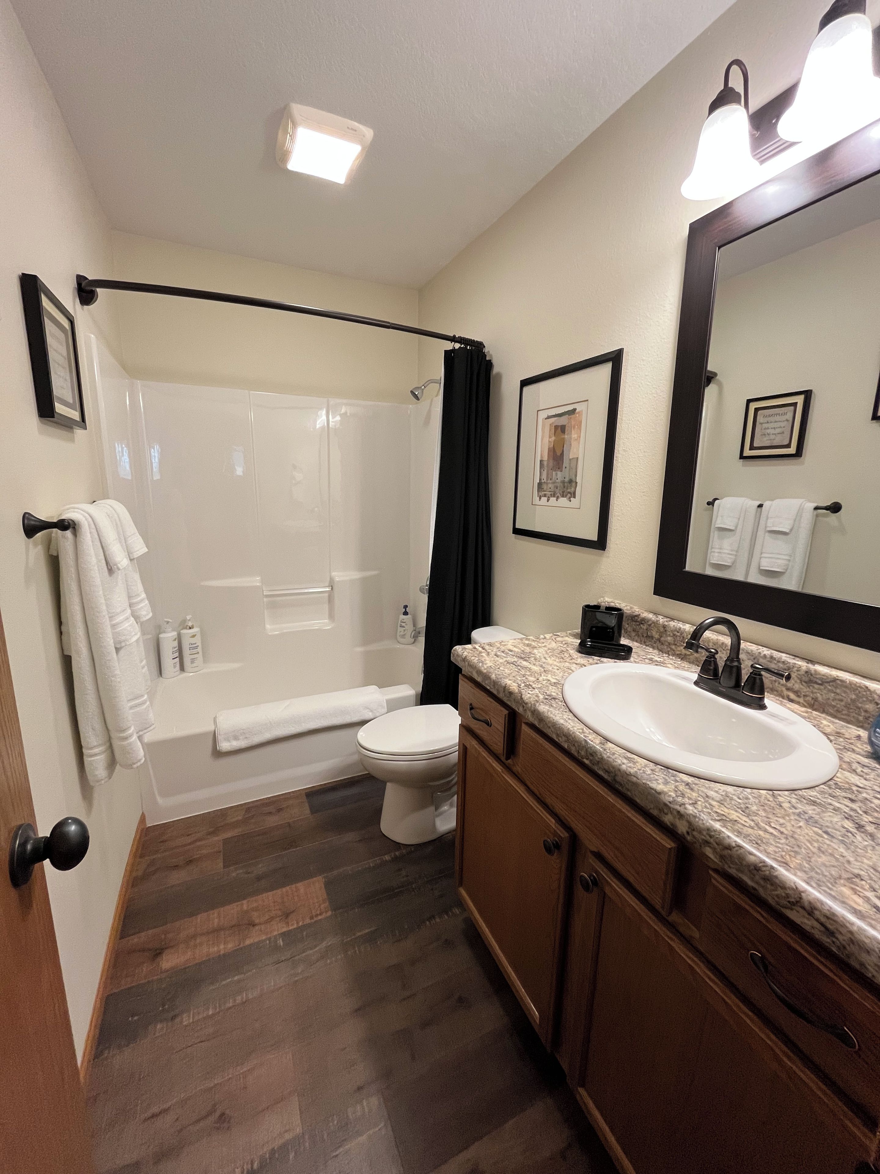 A bathroom with a shower, toilet, sink, and vanity.