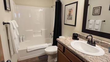 A bathroom with a shower, toilet, sink, and vanity.