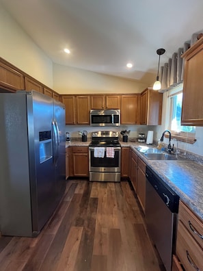 A kitchen with wooden cabinets, stainless steel appliances, and a granite countertop.