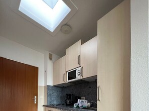 A compact kitchen with a skylight, a microwave, and a coffee maker. - Berliner Ring - Apt. 27 (Wyk auf Foehr)