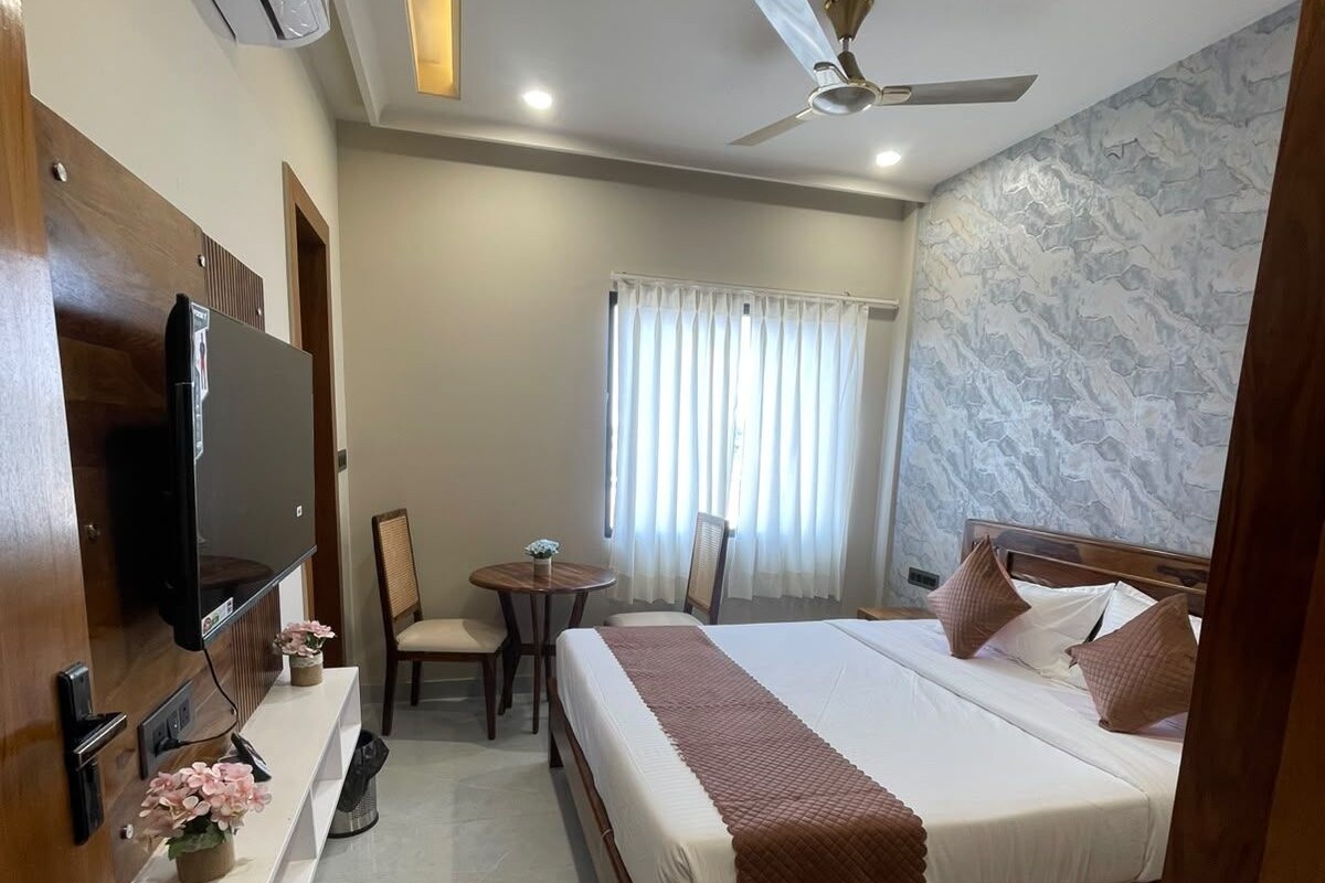 A hotel room with a bed, a desk, a chair, a television, and a ceiling fan.