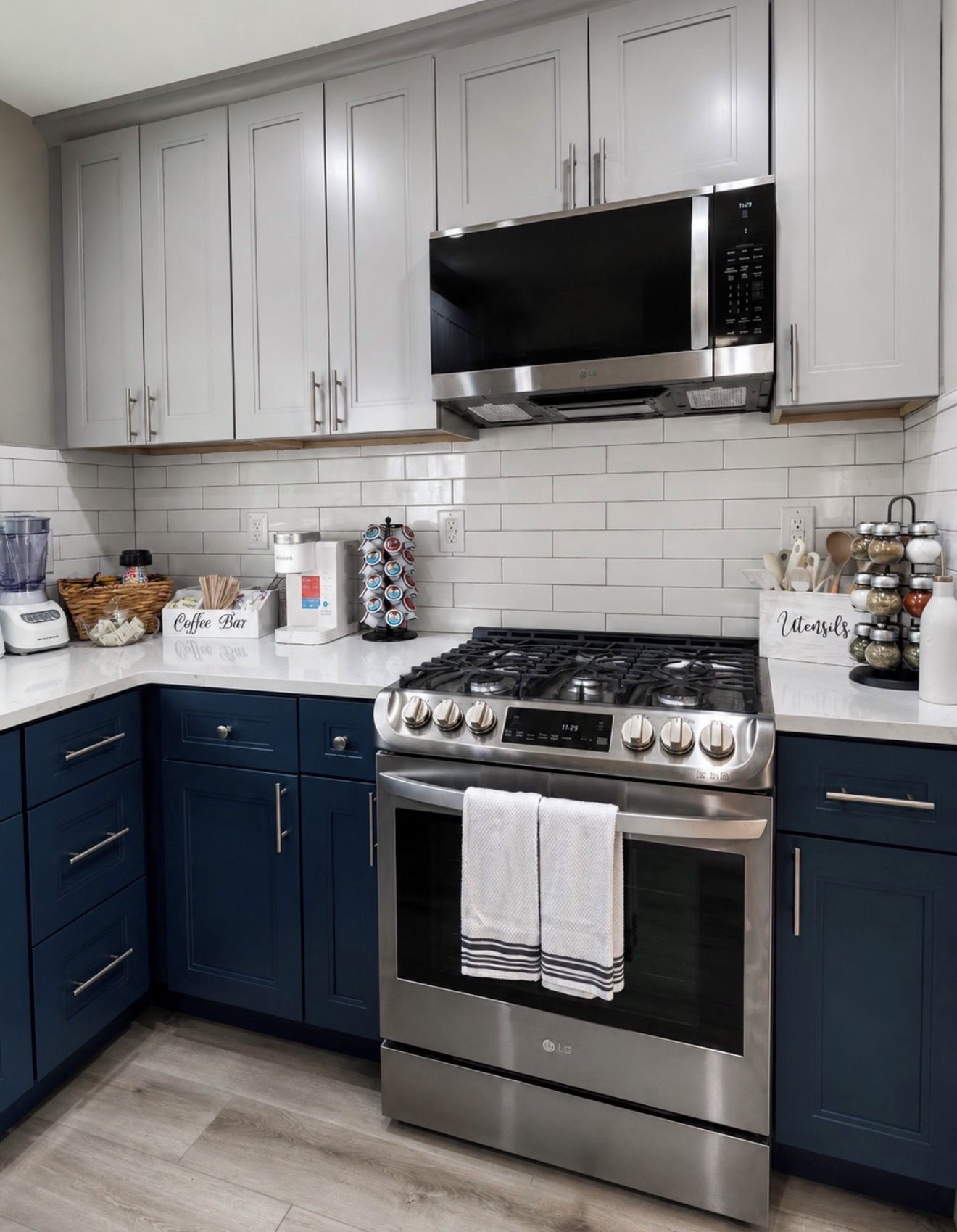 A modern kitchen with white cabinets, a stainless steel stove, and a microwave.