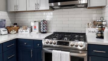 A modern kitchen with white cabinets, a stainless steel stove, and a microwave.