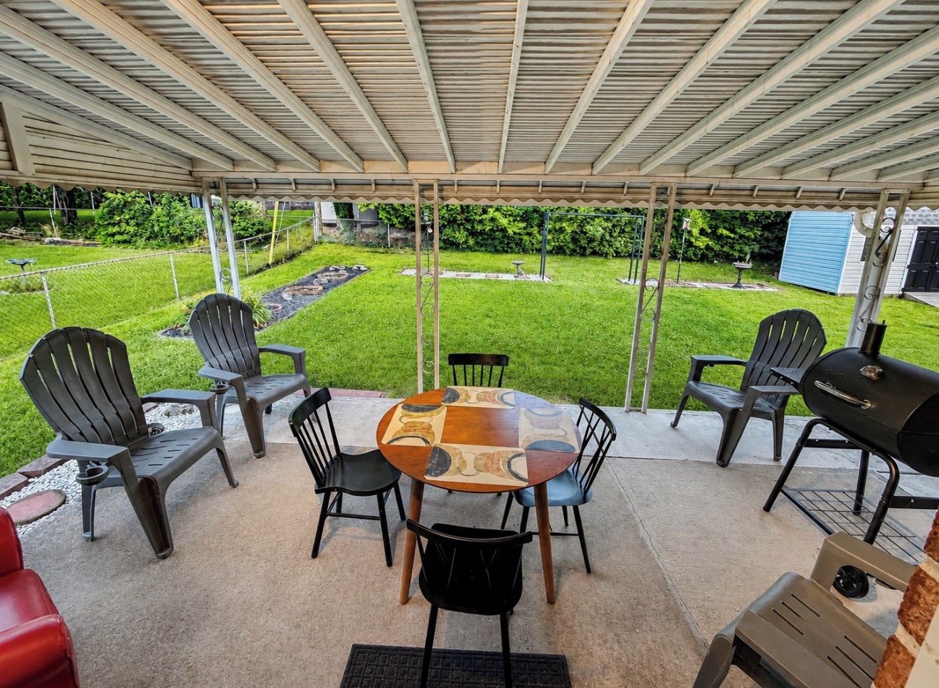 Eine Terrasse im Freien mit überdachter Sitzgelegenheit, einem runden Tisch und Stühlen.