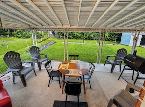Eine Terrasse im Freien mit überdachter Sitzgelegenheit, einem runden Tisch und Stühlen.