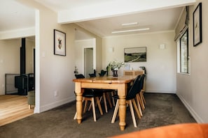 A dining area with a wooden table and chairs, a fireplace, and artwork on the walls. - Sentry Gardens | Huge Private Saltwater Pool | Park-like Gardens | Close to Town (Sentry Hill)