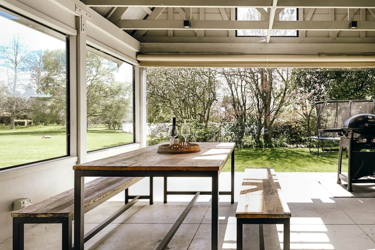 Outdoor covered dining area with seating, bbq and garden view