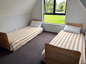A room with two single beds, a window with a view of a green lawn, and a carpeted floor. - Sentry Gardens | Huge Private Saltwater Pool | Park-like Gardens | Close to Town (Sentry Hill)