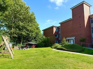 A brick building with a flat roof, a grassy lawn, and a swing set. - Holiday Apartment With 2 Bedrooms (Wyk auf Foehr)